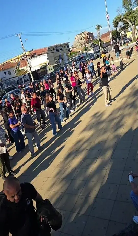 Clase abierta de salsa al aire libre con muchas personas siguiendo al profesor
